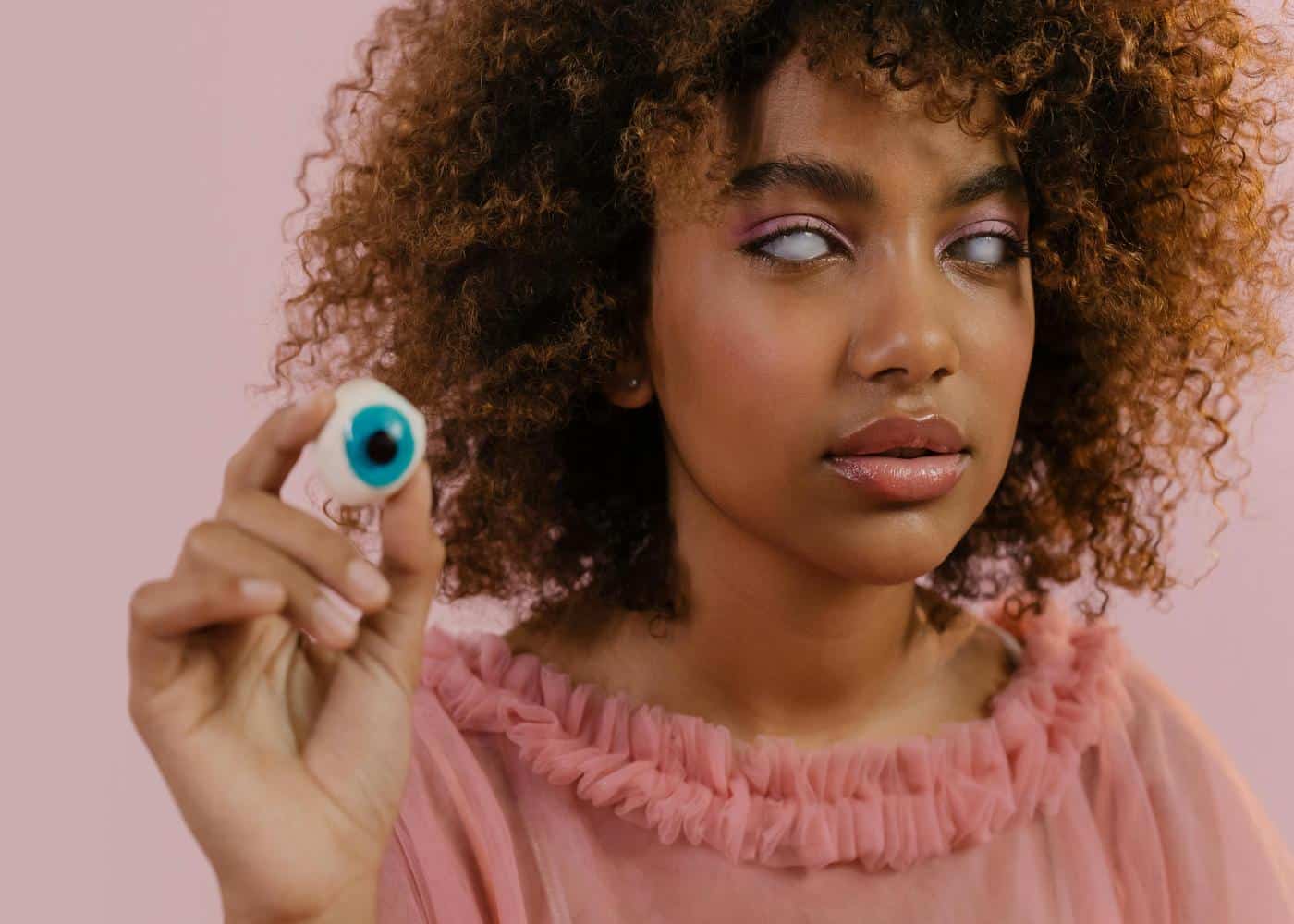 Cosplay Contacts Safety: Woman wearing white contacts and holding a fake eye