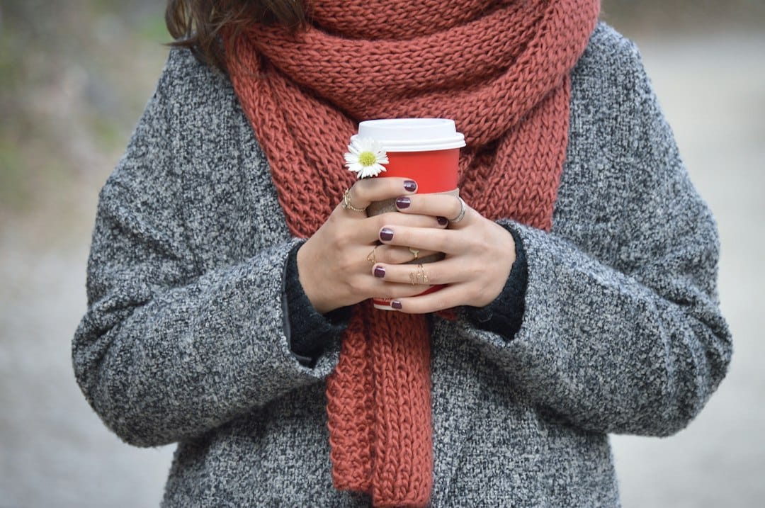 Person wearing a wool coat and knitted scarf