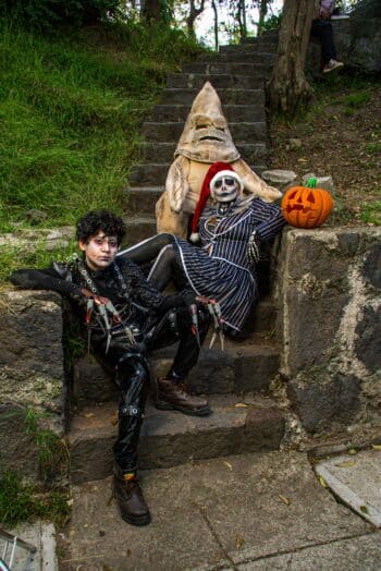 Three people in Halloween character costumes posing together on outdoor steps