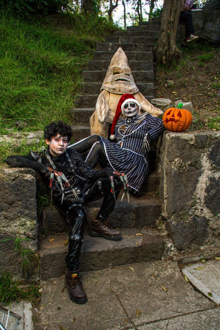 Three people in Halloween character costumes posing together on outdoor steps