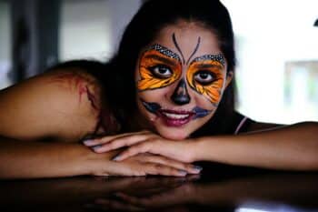 Colourful butterfly face paint with dark theatrical details