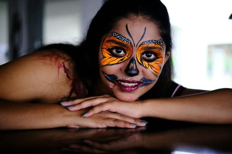 Colourful butterfly face paint with dark theatrical details