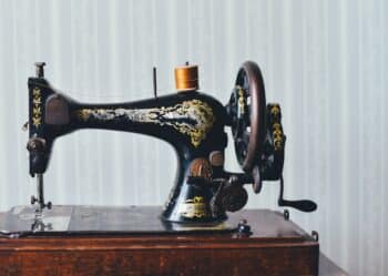 Vintage black sewing machine with gold decoration and a spool of thread