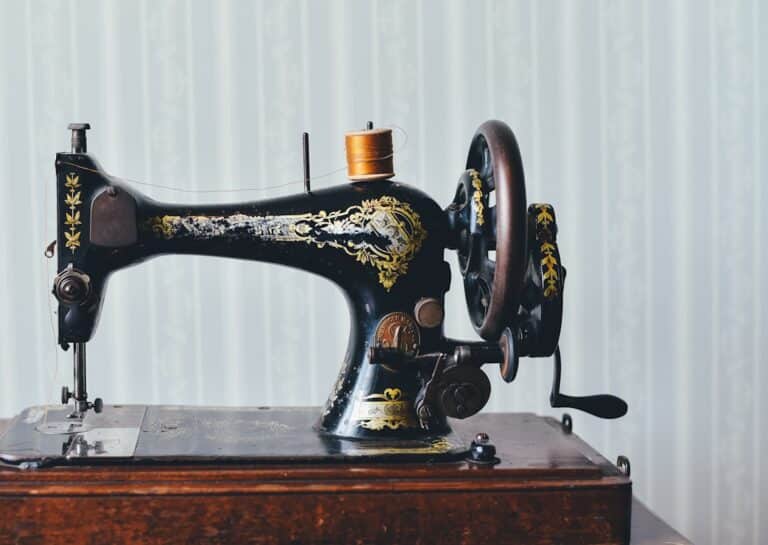 Vintage black sewing machine with gold decoration and a spool of thread