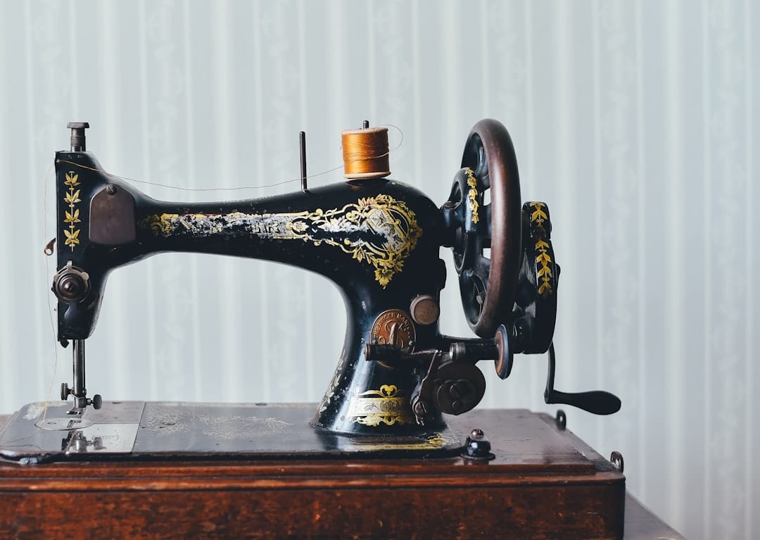 Vintage black sewing machine with gold decoration and a spool of thread
