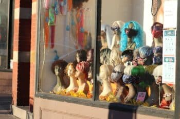 Colourful wigs displayed on mannequin heads in a shop window