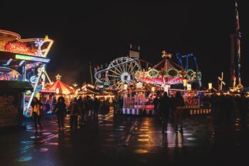 Crowds walking through a brightly lit amusement park at night