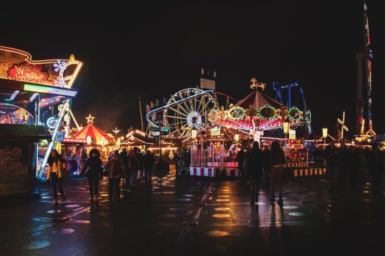 Crowds walking through a brightly lit amusement park at night